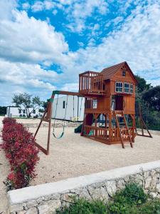 un parque infantil con una estructura de madera en la arena en Novak House, en Pakoštane