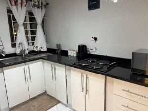 a kitchen with white cabinets and a black counter top at Southcentral Apartments in Livingstone +3 photos