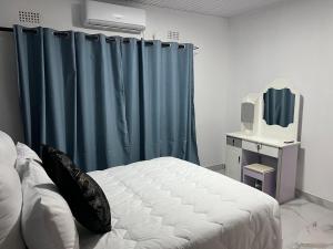 a bedroom with a bed and a blue curtain at Southcentral Apartments in Livingstone