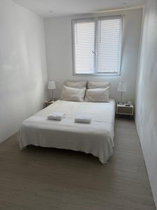 a white bedroom with a bed with two towels on it at Location dans résidence privée,sécurisée ,parking gratuit , 1 minute du tramway, à 9 minute du centre ville, accessible à plusieurs transports in Nice