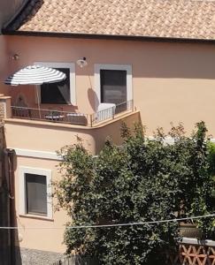 a building with a balcony with an umbrella and chairs at Bella casa d'epoca in splendido borgo siciliano in Piraino