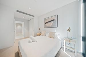 パースにある1BR Apartment in the Heart of the CBDの白いベッドとテーブルのある白い寝室