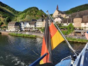 a boat with a flag in the water near a town at Ferienwohnung Götz in Bruttig-Fankel +10 photos