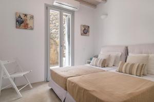 a white bedroom with a large bed and a window at Luxury villa with stunning views above Kalo Livadi in Mýkonos City +92 photos