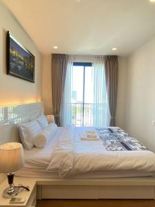 a bedroom with a large white bed with a window at 清迈市区Astra condo 屋顶无边泳池可步行至夜市 in Chiang Mai