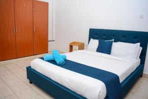 a bedroom with a large bed with a blue headboard at Relax in this Karatina,Nyeri comfy, Quiet and stylish apartment in Karatina