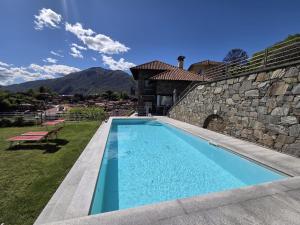 a swimming pool in a yard next to a stone wall at Appartamento Sofia in Mergozzo