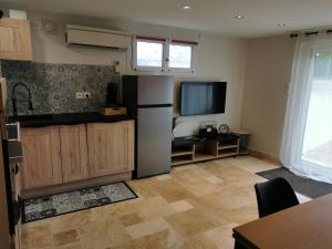 a kitchen with a refrigerator and a tv on the wall at La Cigaline in Anneyron