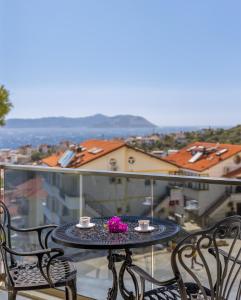 a table with two cups and flowers on a balcony at Happy Kaş Apart in Kaş