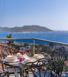 a table with chairs and wine glasses on a balcony at Happy Kaş Apart in Kaş