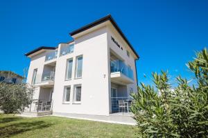 a white apartment building with a blue sky at Apartments Villa Navi in Bibinje