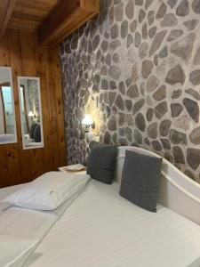 ein Bett in einem Zimmer mit einer Steinwand in der Unterkunft Rem's Pension in Râșnov + 109 Fotos