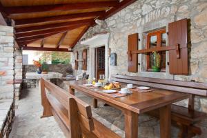 a dining room with a wooden table and benches at Villa Favola, a rustic retreat surrounded by beautiful nature in Vinež