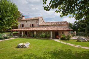 a large stone house with a grass yard at Villa Favola, a rustic retreat surrounded by beautiful nature in Vinež