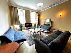 Una sala de estar con sofás azules y una mesa. en Cheerful 5 Bedroom House Close to Central West End and Parking, en Glasgow