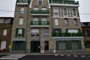 un alto edificio in mattoni con finestre e balconi verdi di Studio neuf à louer à Dinard 3 nuits minimum a Dinard