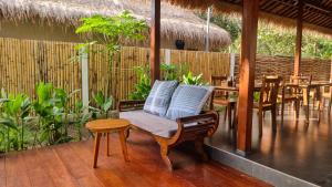 Un porche con una silla y mesas y una valla. en Ananda B&B, en Gili Air