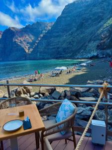 a patio with a table and chairs and a beach at marina in Acantilado de los Gigantes