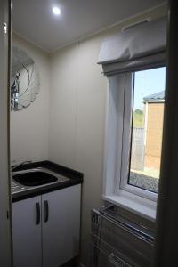 a small kitchen with a sink and a window at Amazing Lodge with Hot Tub in Stowmarket +18 photos
