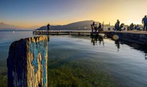 a wooden pole in the water with people on a pier at La petite Venise des Alpes, Ultra centre 1 à 5 Pers in Annecy