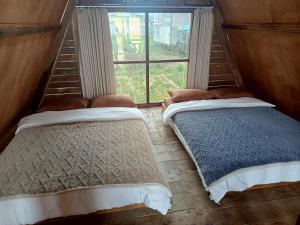 two beds in a room with a window at Cabin atas awan in Dieng