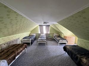 a attic room with three beds and a window at Karakol Riviera in Karakol