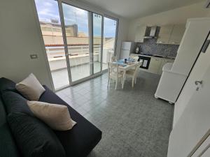 a living room with a couch and a kitchen with a table at SolMarina Holiday House in Marina di Ragusa