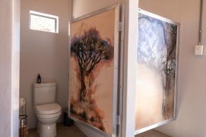 a bathroom with a shower door with a tree painting at Spreetshoogte Campsite in Namibgrens