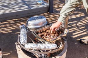 a person is cooking food on a grill at Spreetshoogte Campsite in Namibgrens