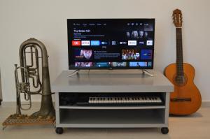 a tv on a stand with a keyboard and a guitar at La Casetta di via Tasso in Piombino +28 photos