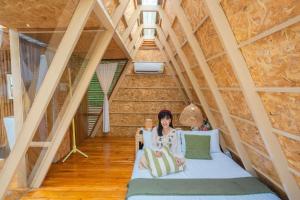 a woman sitting on a bed in a attic at บ้านธารหมอก แอท สะปัน in Ban Huai Ti