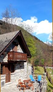 a cabin with a deck and two chairs and a table at Baita "il Fieniletto" in Bannio