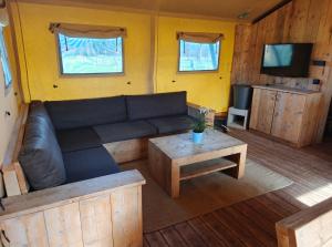 a living room with a couch and a coffee table at Glampingtent 6 persoons Lindershoeve Bergeijk in Bergeijk +14 photos