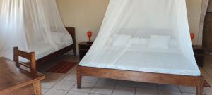 a bedroom with a bed with a canopy at Hôtel de la Plage in Ambolomailaka