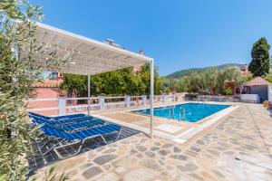 a swimming pool with two blue chairs and a white canopy at Aretousa Studios & Apartments in Skopelos Town