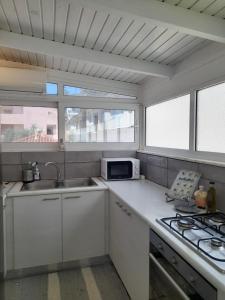 a white kitchen with a sink and a microwave at The Blue Door in Lixouri