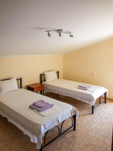 two beds in a room with two tables at Dina Apartments in Fanari