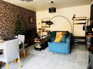 a living room with a blue couch and a brick wall at Chez Simone in Valréas