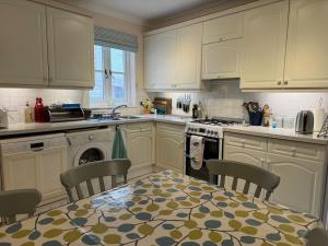 a kitchen with white cabinets and a table with chairs at Gulls, charming seaside cottage, centrally located in Seaview