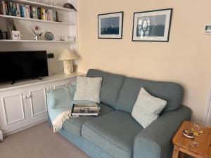 a living room with a blue couch and a tv at Gulls, charming seaside cottage, centrally located in Seaview