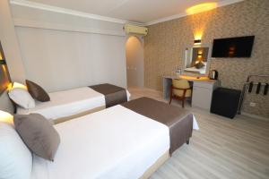 ein Hotelzimmer mit zwei Betten und einem Schreibtisch in der Unterkunft Artan Hotel in Isparta