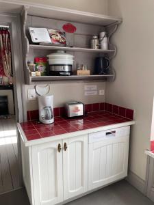 eine Küche mit weißen Schränken und roten gefliesten Arbeitsplatten in der Unterkunft Appartement Le feron in Vic-sur-Cère + 12 Fotos