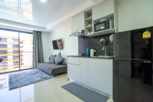 a kitchen and living room with a couch and a microwave at The Urban Tropical Apartments in Mai Khao Beach