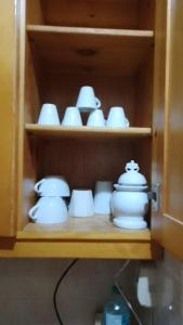 a group of white cups and saucers on a shelf at Agora House for men only 仅限男性 in Alexandria