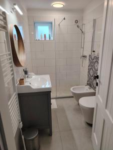 un bagno bianco con lavandino e WC di Pupi Apartmanház a Balatonlelle
