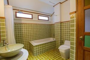 a green tiled bathroom with a sink and a toilet at Rich Lanna House in Chiang Mai