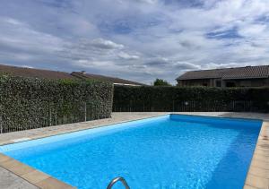 a blue swimming pool in front of a fence at Lumaïa - Vue cité, terrasse & Piscine in Carcassonne