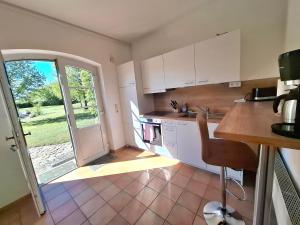 a kitchen with white cabinets and an open door at Farm-Chalets Apartment Park in Renzow