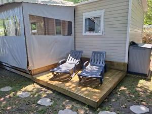加斯泰Mobil-home Camping Siblu La Reserve ****的两把椅子坐在房子旁边的甲板上