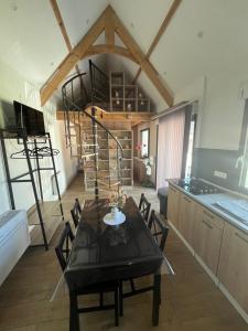 a dining room with a table and a spiral staircase at La datcha in Drouvin-les-Marais